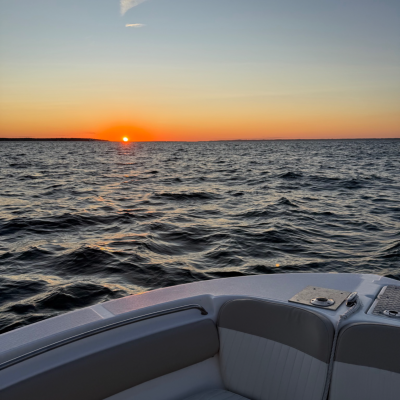 Cape Cod Sunset Cruise Over Cape Cod Bay Sun setting over Cape Cod Bay as viewed from a private boat, with calm ocean waters and colorful evening skies creating a peaceful sunset cruise experience.